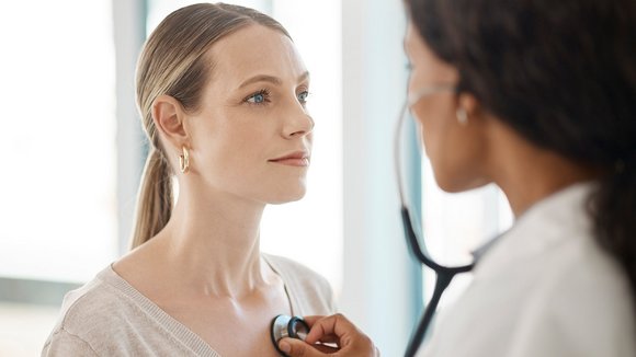 Eine Ärztin hört eine Patientin mit dem Stethoskop ab.