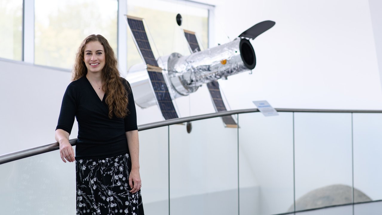 Laura Kreidberg steht vor einem Modell eines Satelliten