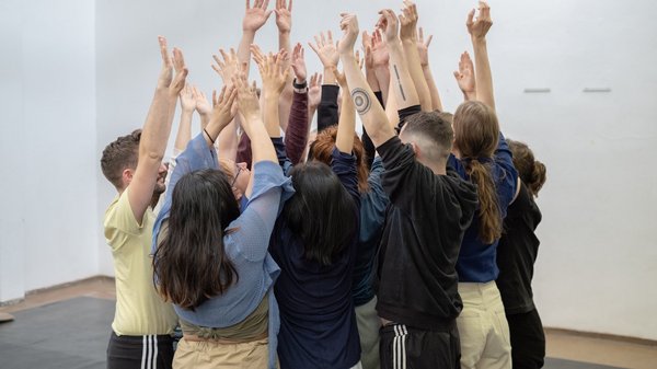 Eine Gruppe junger Menschen hebt die Hände in die Luft