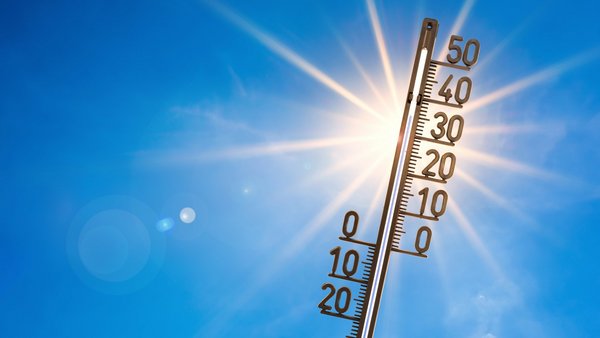 Thermometer mit blauem Himmel und Sonne im Hintergrund