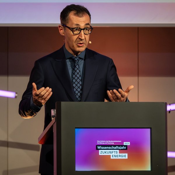 Bundesminister für Bildung und Forschung Cem Özdemir steht an einem Pult und hält eine Rede.