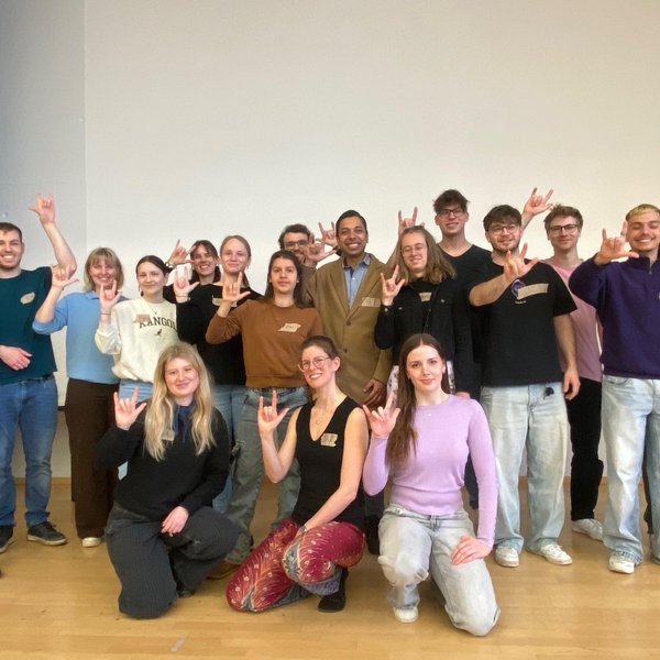 Die Studierenden von Energialogue posieren für ein Gruppenbild und zeigen das internationale Zeichen für Solidarität mit allen Gebärdensprachler:innen.