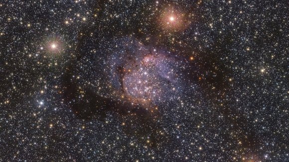 Hinter dem schwachen orangefarbenen Leuchten des Nebels Sh2-54 ist auf diesem neuen Infrarotbild eine Vielzahl von Sternen zu erkennen.