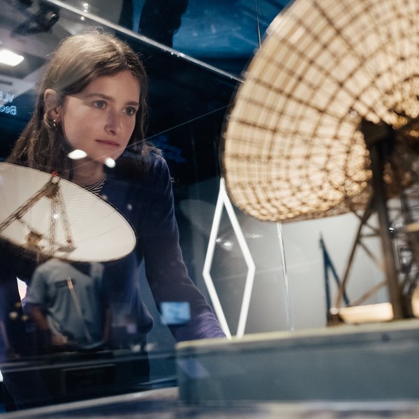 Eine Frau schaut sich ein Modell eines Radioteleskops an. 