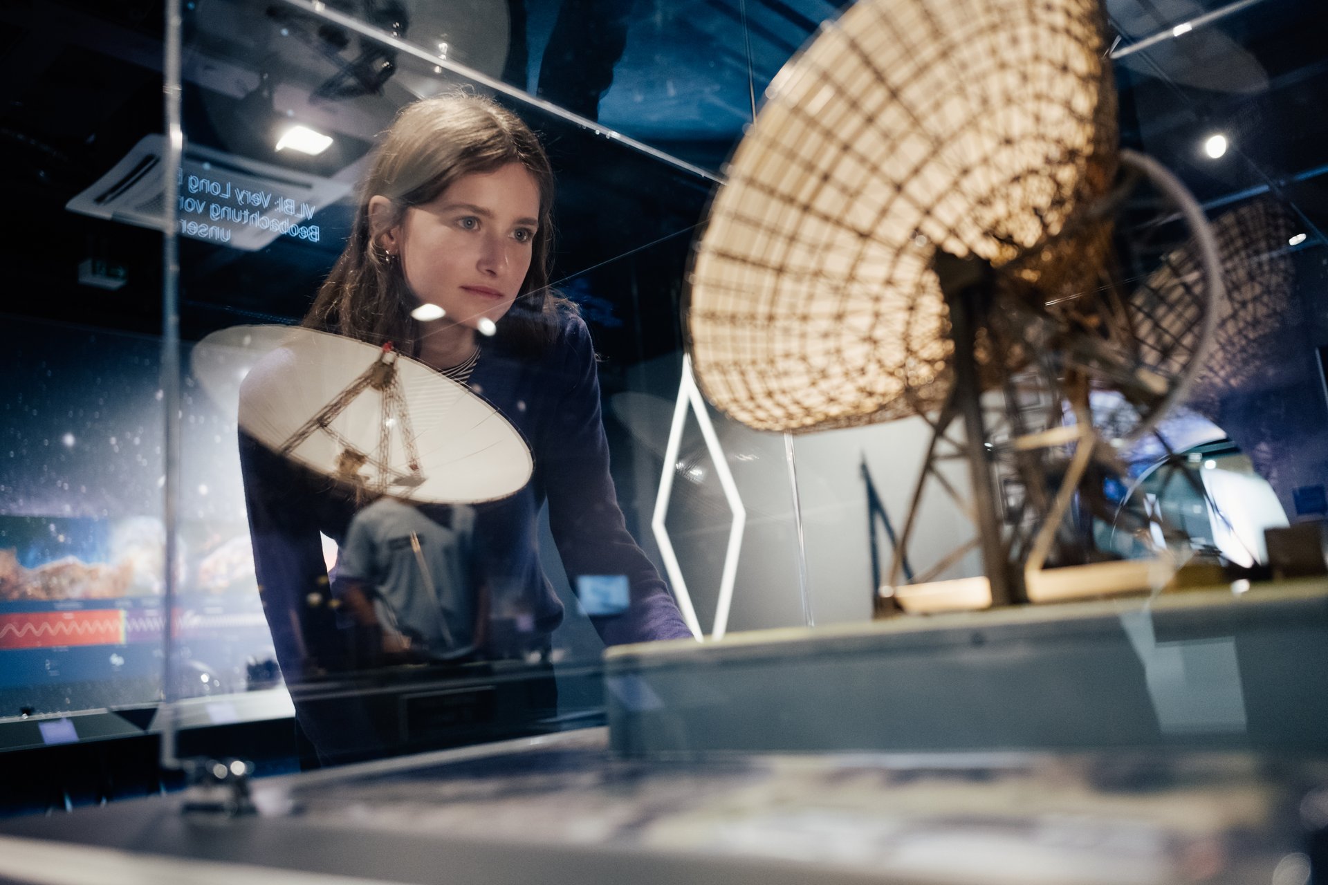 Eine Frau schaut sich ein Modell eines Radioteleskops an. 