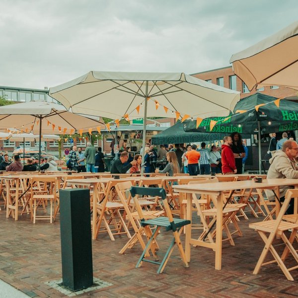 Zahlreiche Menschen sitzen an Tischen auf einem Straßenfest