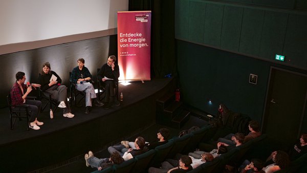 Vier Personen diskutieren in einem Kinosaal vor einer Schulklasse.