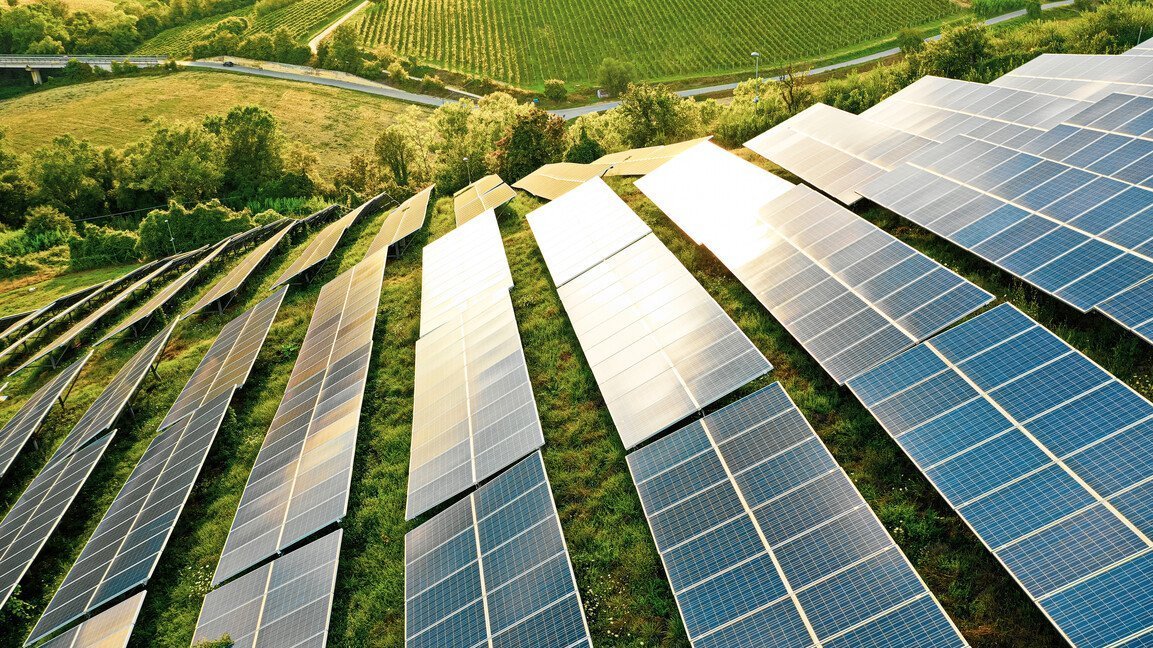 Sonnenkollektoren an einem grünen Hang.