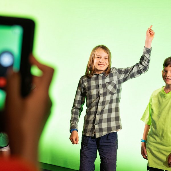 Zwei Schüler stehen vor einem Greenscreen.