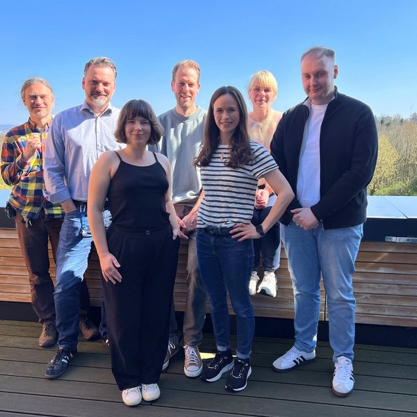 Eine Gruppe von sieben Personen gemischten Alters posiert für ein Gruppenfoto im Freien.