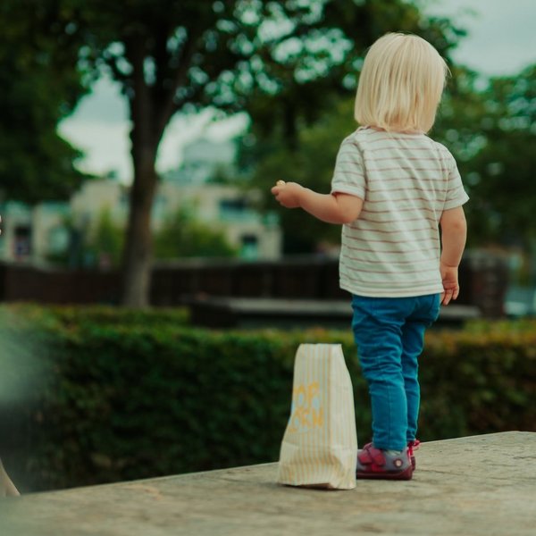 Kind steht auf der Ladefläche eines Autos, ein Mann steht daneben und macht ein Handyfoto von dem Kind.