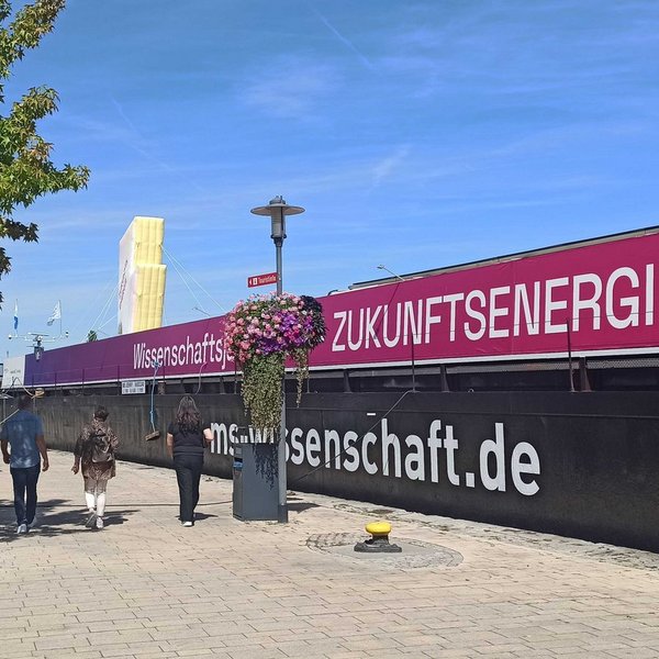 Schiff mit der Aufschrift "Wissenschaftsjahr 2025 – Zukunftsenergie" einer Uferpromenade