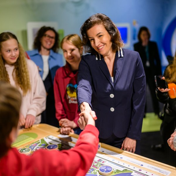 Bundesministerin für Forschung, Technologie und Raumfahrt Dorothee Bär gibt einem Jungen die Hand.