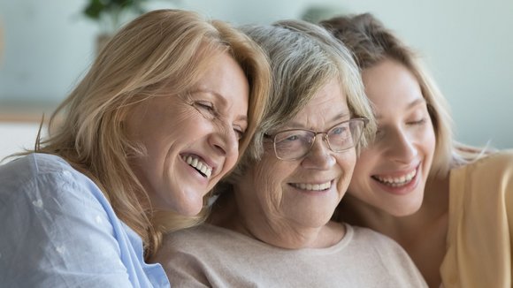 Drei Frauen in verschiedenem Alter sitzen zusammen und lachen.