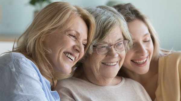 Drei Frauen in verschiedenem Alter sitzen zusammen und lachen.
