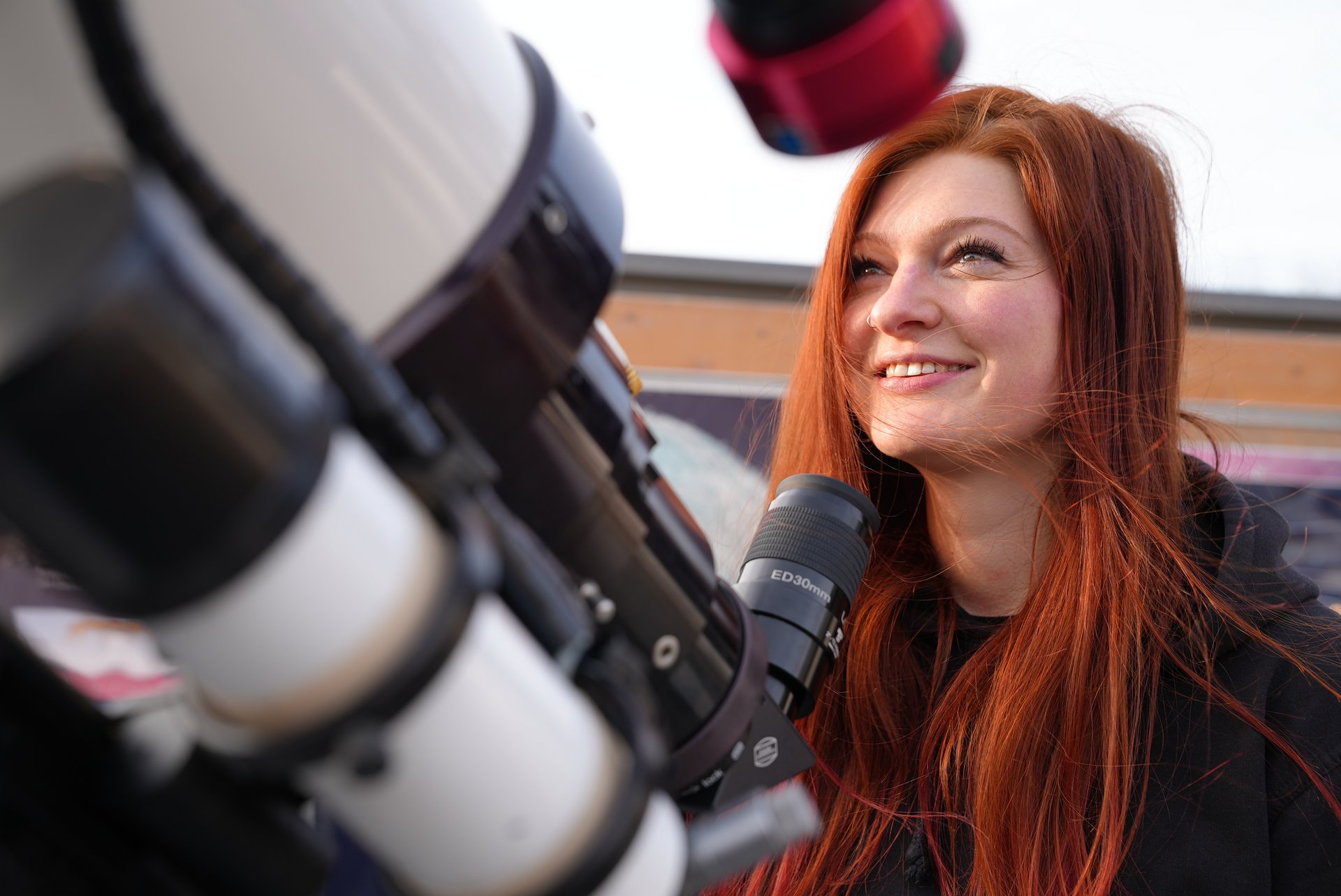 Isabella Graßl vor einem Teleskop.