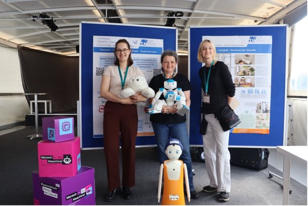 Gruppenfoto des Projektteams. Mittige Person hält einen kleinen Roboter in den Händen, vor der Personengruppe ist ein weiterer kleiner Roboter platziert.